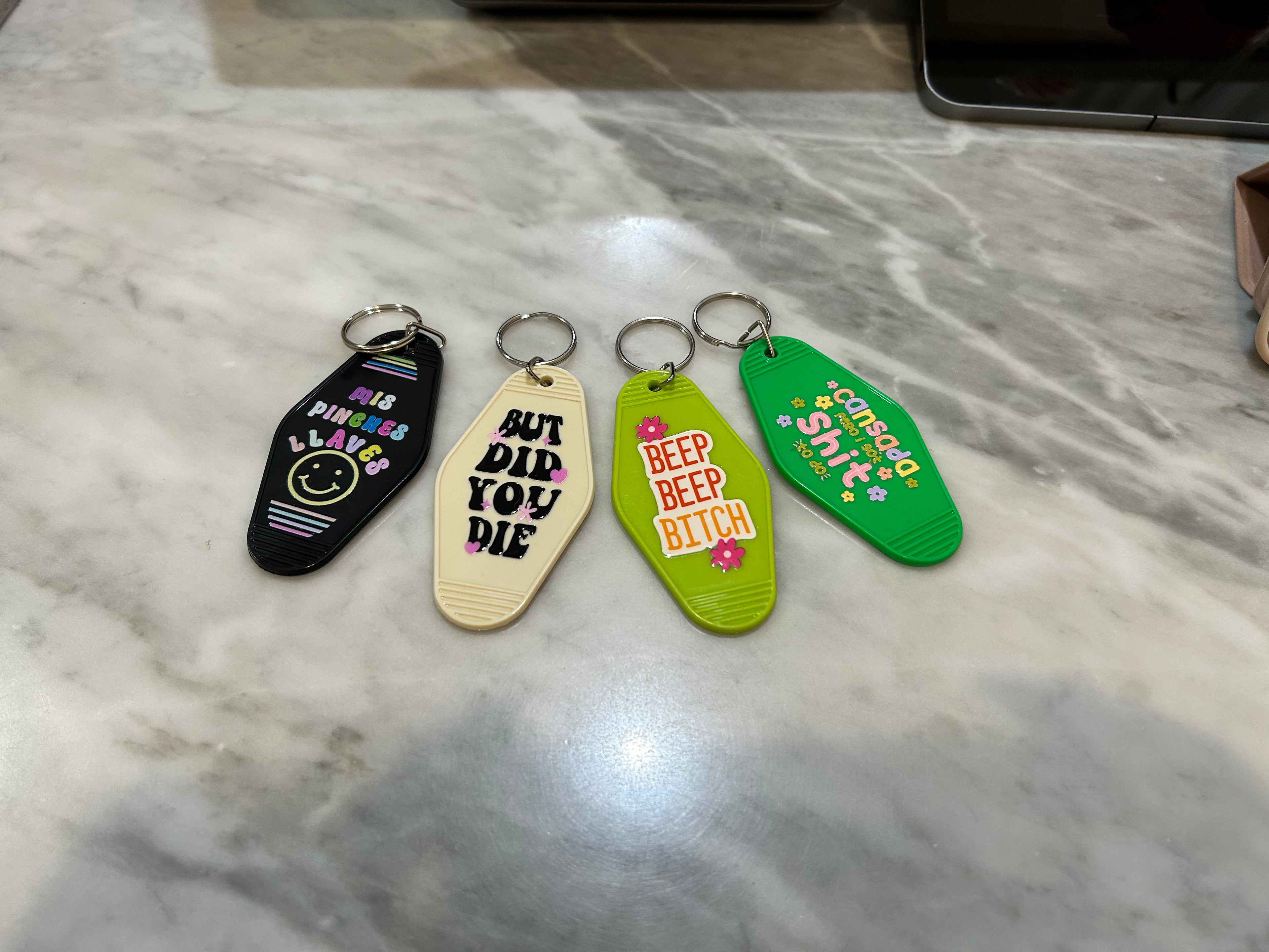 Four colorful keychains with text on a marble surface