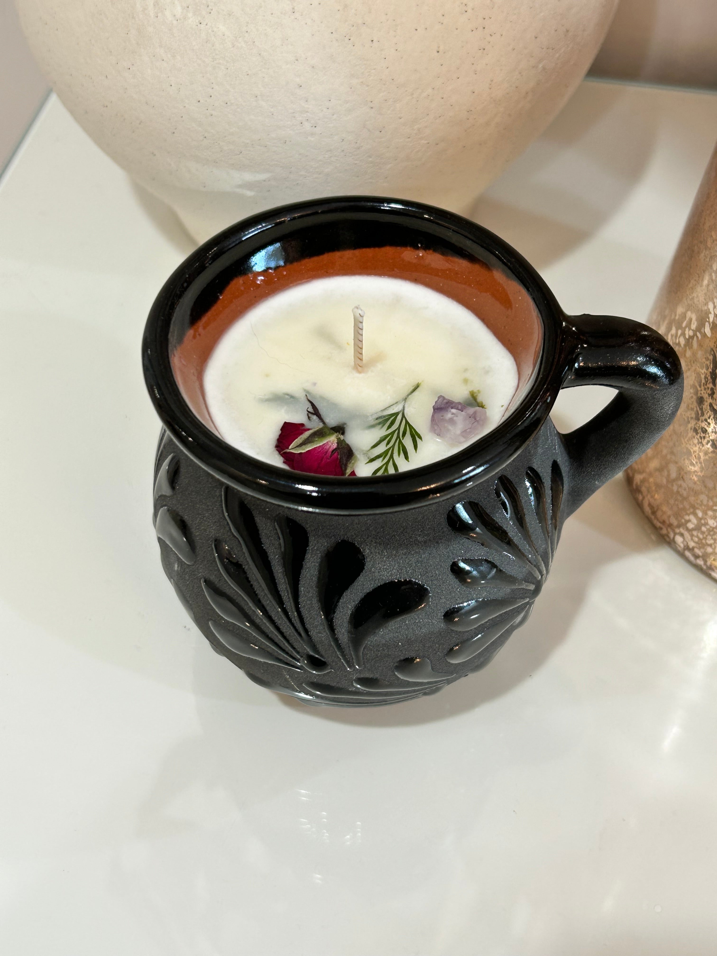 Decorative talavera candle in a black, ceramic, Mexican container with intricate patterns on a neutral background.