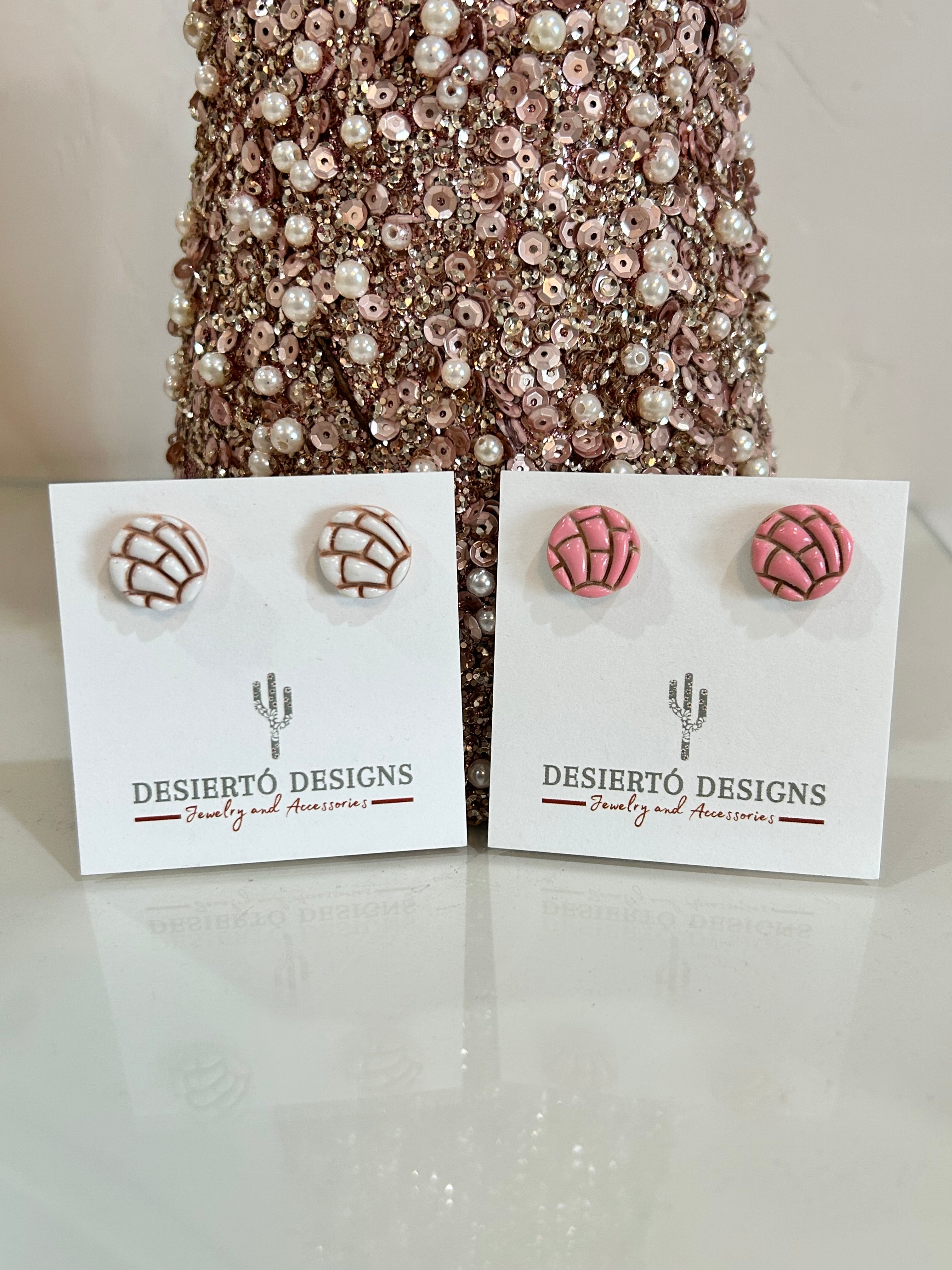 Pink and white concha stud earrings on backing cards with a glittery background.