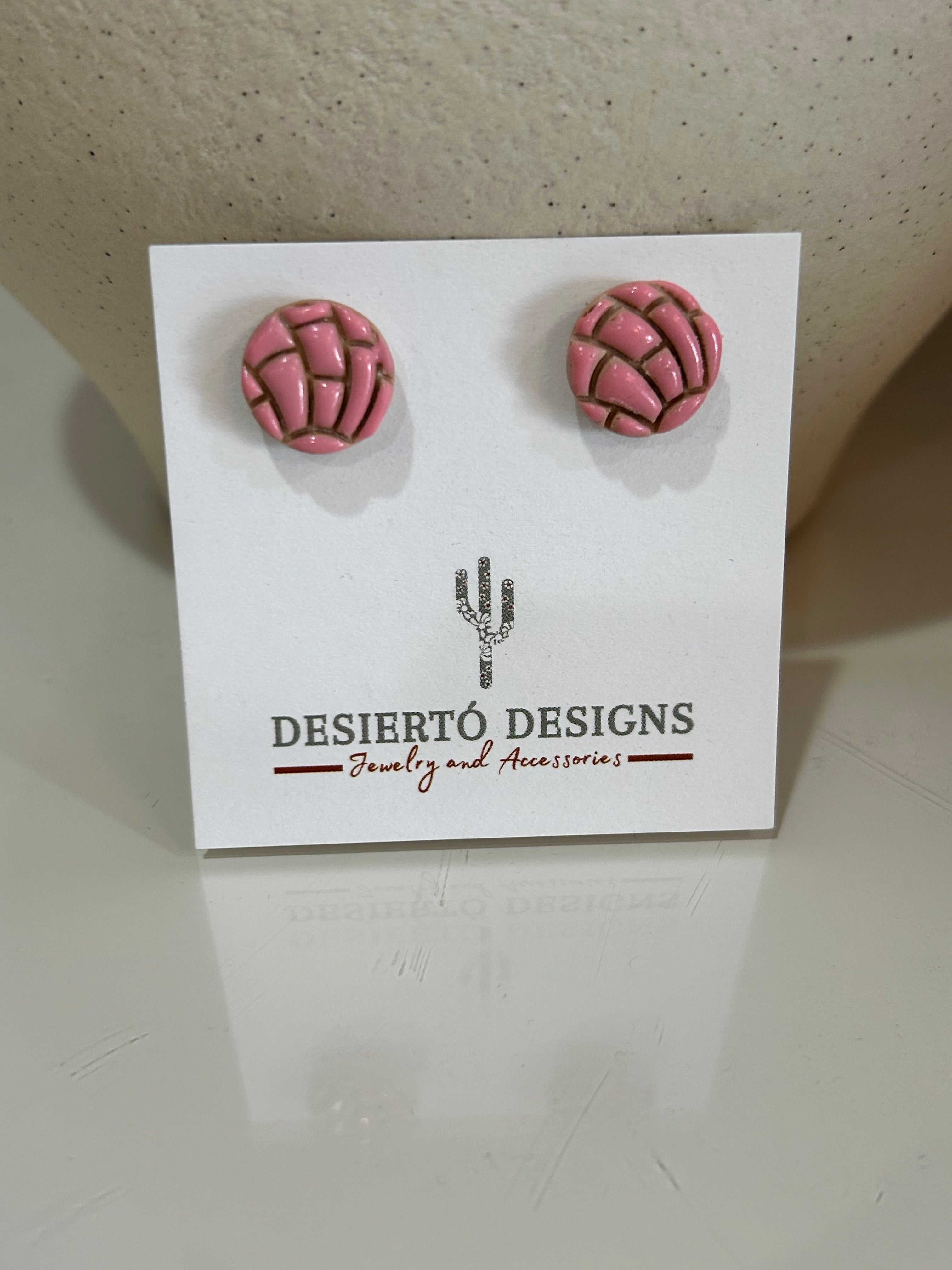 Pink concha stud earrings pair on a backing card.