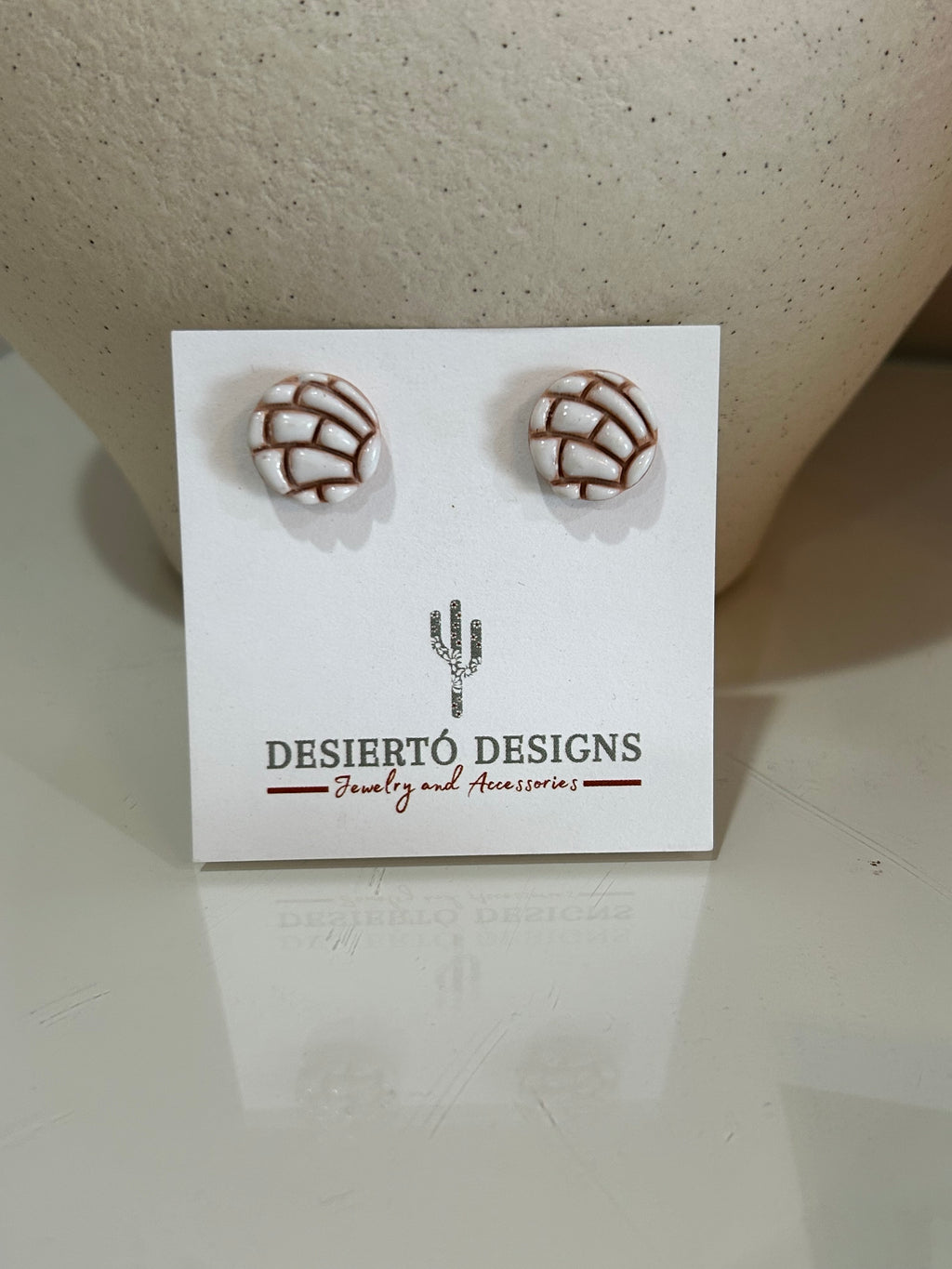 White concha stud earrings pair on a backing card.