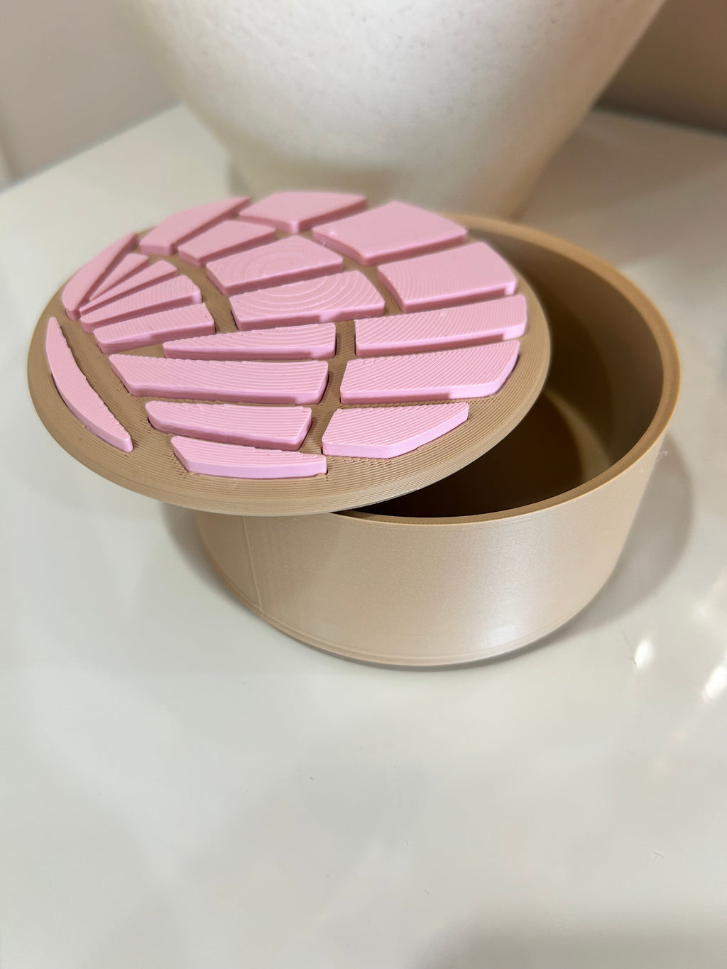 Pink and beige concha trinket box with lid open on a white surface.