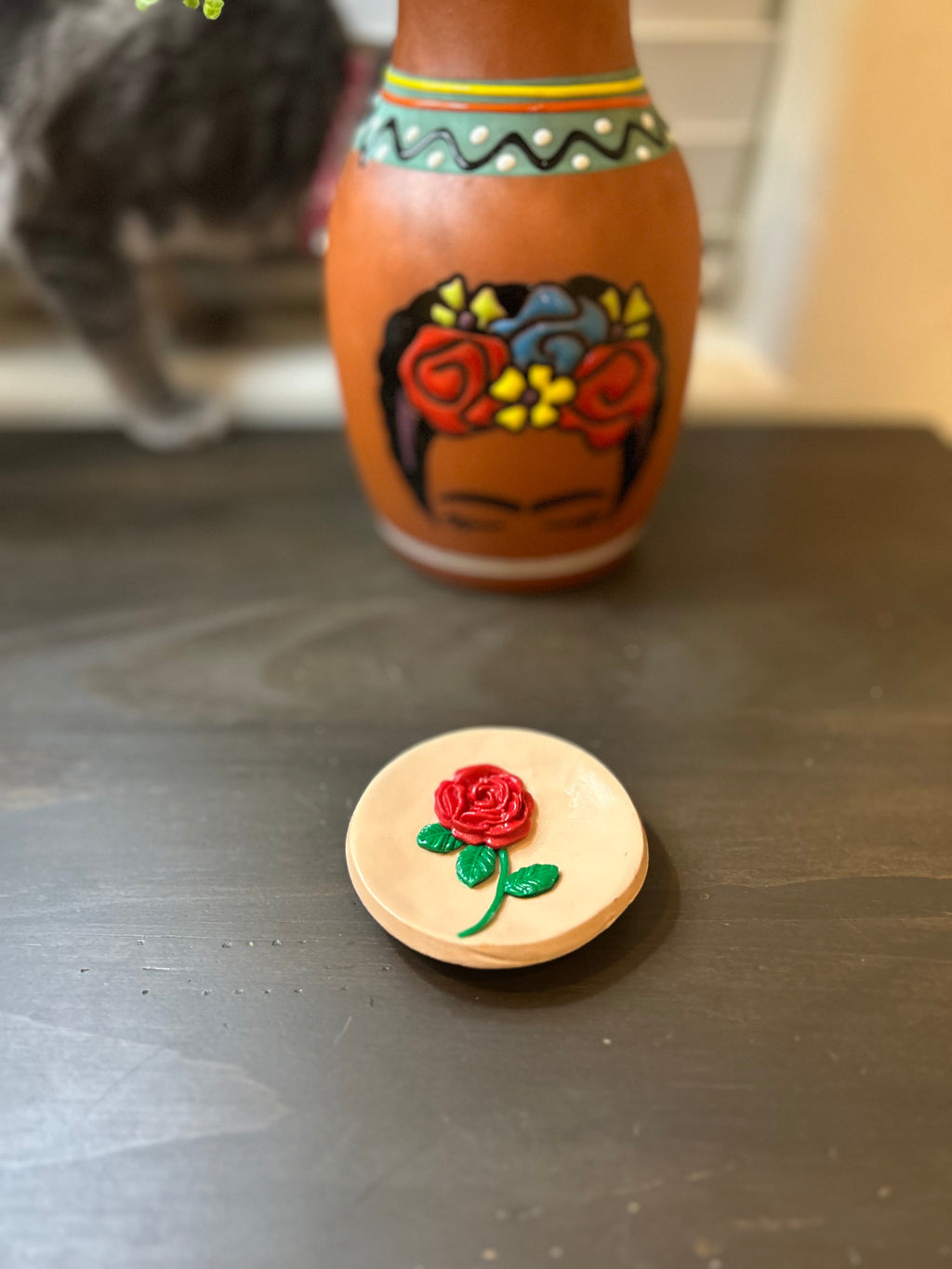 Round Mazapan trinket dish with a centered red rose design on a gray surface.