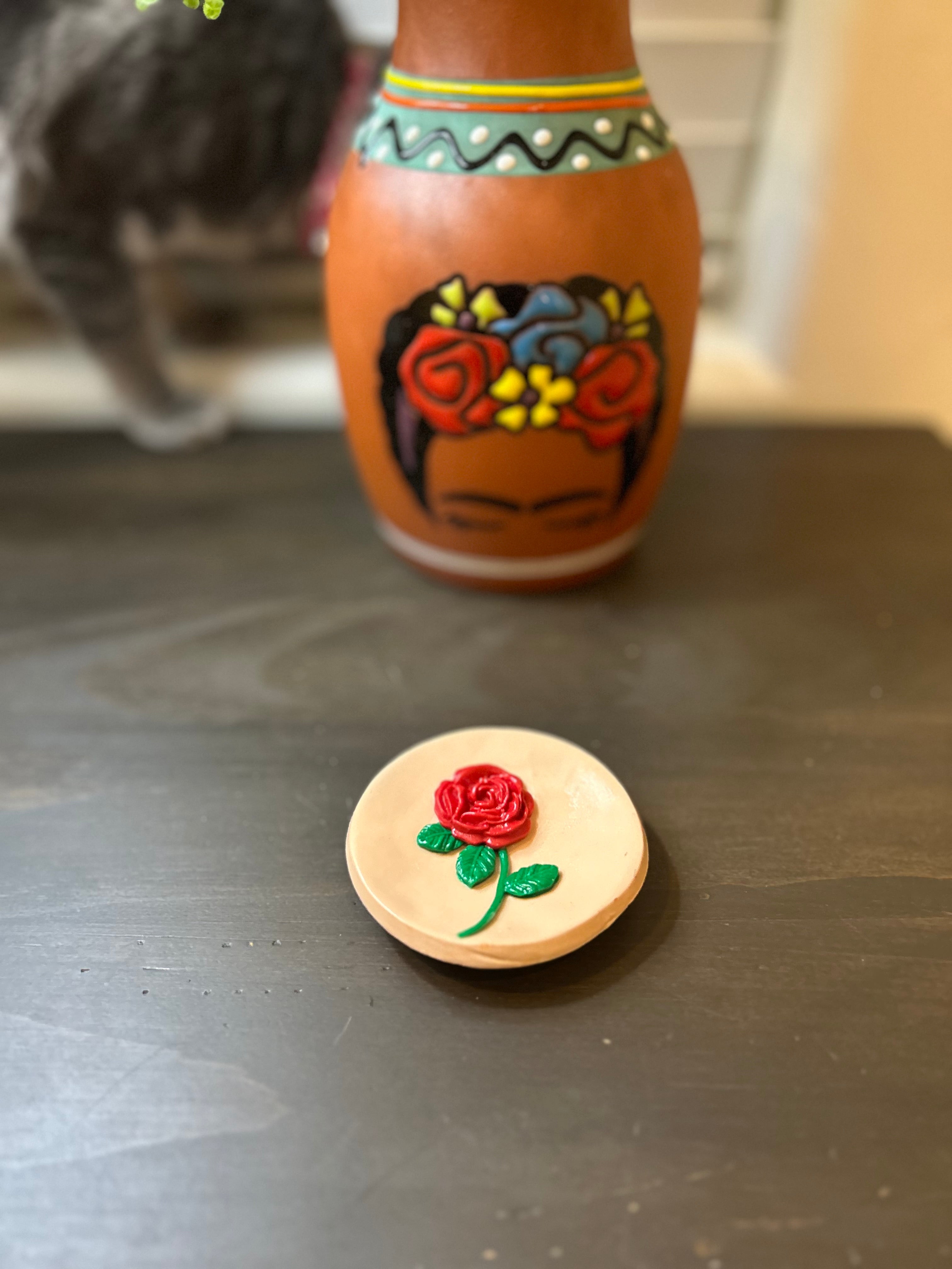 Round Mazapan trinket dish with a centered red rose design on a gray surface.